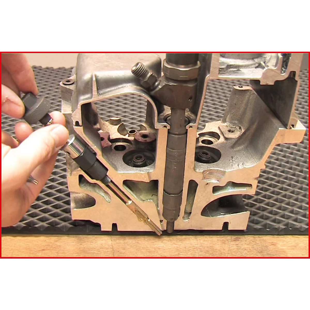 Querschnitt durch einen Motor. Eine Hand hält einen Injektor; daneben ein zweiter. Im Hintergrund das Innere des Motorblocks.